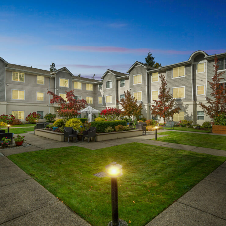 Tranquil courtyard with seating, gardens, and soft lighting at a welcoming retirement community.