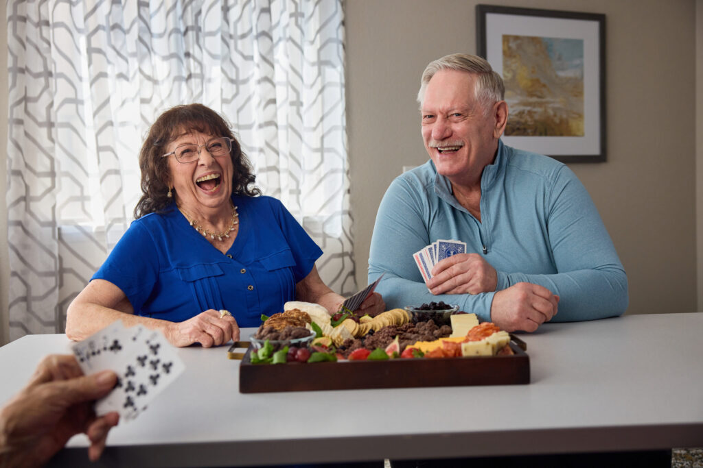 Seniors enjoying a friendly card game with snacks in a bright, welcoming room.