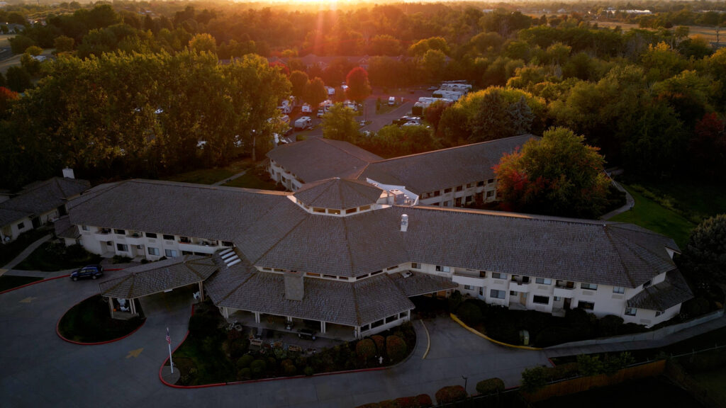 Retirement community surrounded by lush trees and peaceful sunset, offering a welcoming atmosphere.