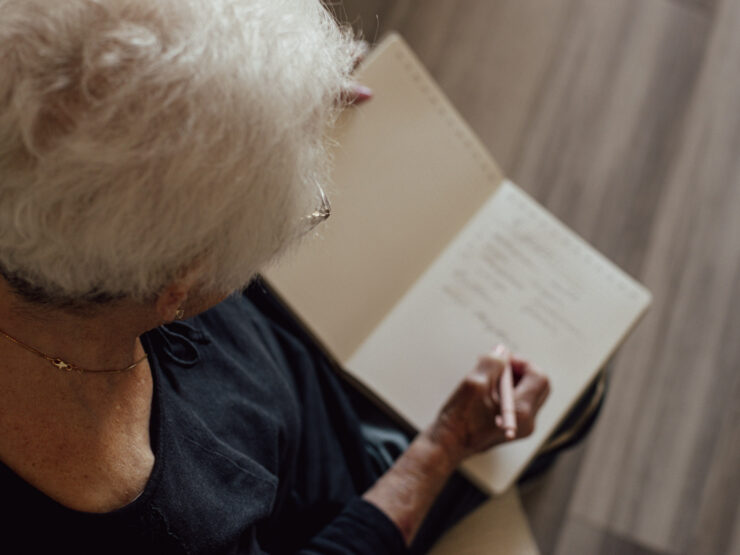 A resident enjoys a peaceful moment, writing in a notebook, surrounded by warmth and community.