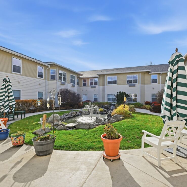 A serene courtyard invites relaxation, featuring a fountain, colorful plants, and comfortable seating.