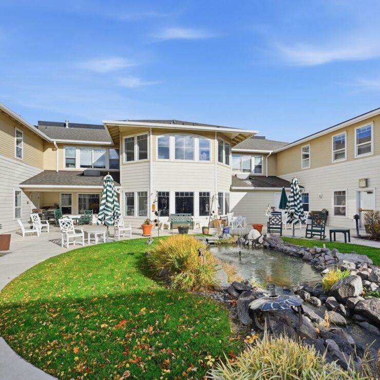 A welcoming courtyard features vibrant greenery and a peaceful pond, perfect for relaxation and community.