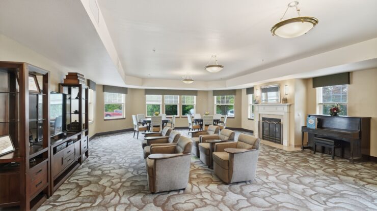 A welcoming lounge features comfortable seating, bright windows, and a piano, fostering community and connection.