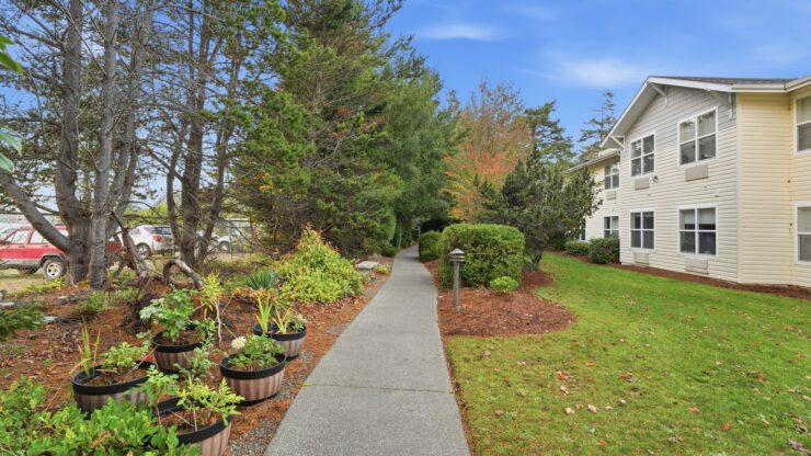 A welcoming pathway lined with greenery leads to a charming residence, inviting community and comfort.