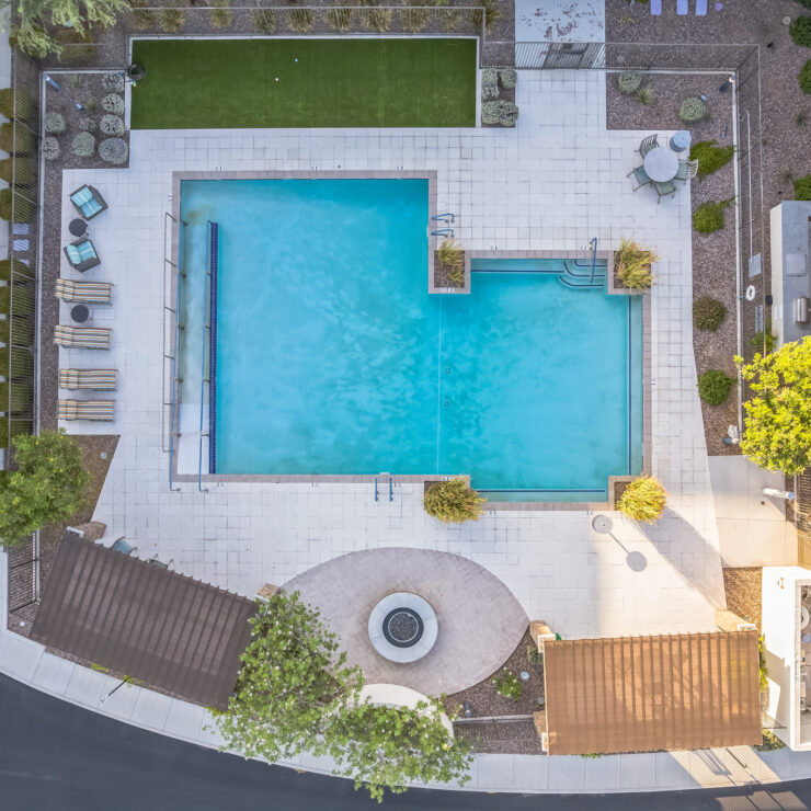 A serene outdoor space featuring a sparkling pool, surrounded by lush greenery and inviting seating areas.