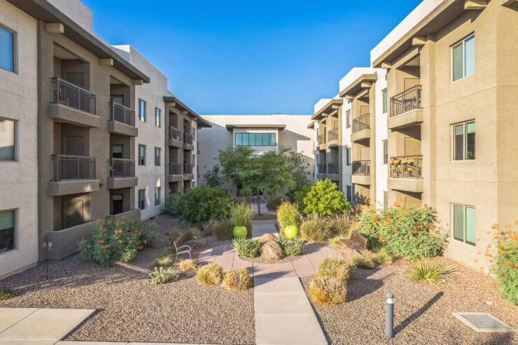 A vibrant courtyard invites connection, surrounded by welcoming residences and lush greenery.