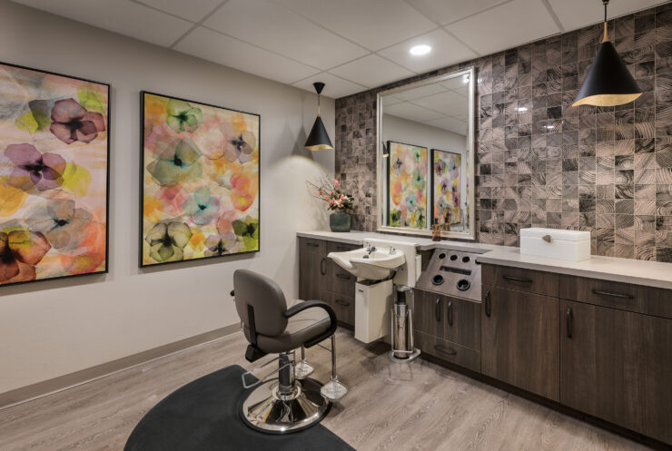 Bright and inviting salon space, featuring floral art and comfortable styling chairs, fostering community warmth.