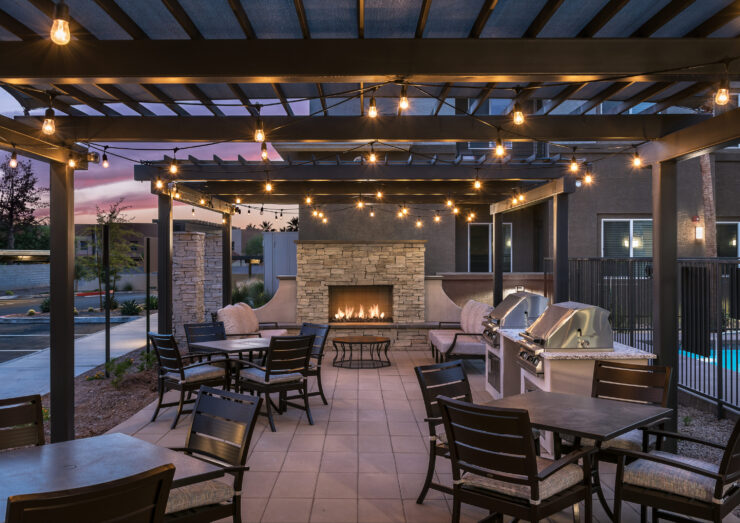 A welcoming outdoor space with cozy seating, warm lights, and a fireplace, perfect for community gatherings.