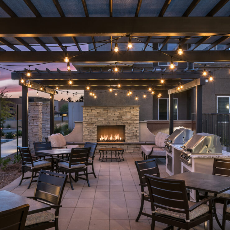 A welcoming outdoor space with cozy seating, warm lighting, and a fireplace, perfect for community gatherings.