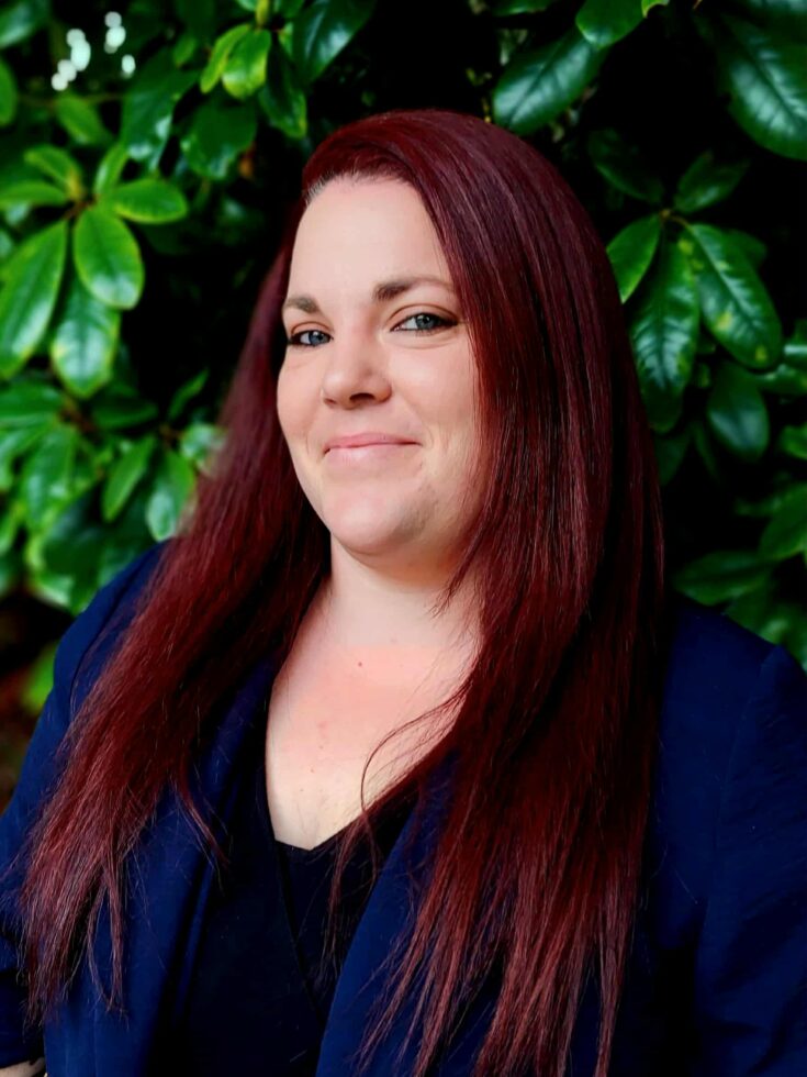 A warm smile against lush greenery reflects a welcoming community spirit and caring atmosphere.