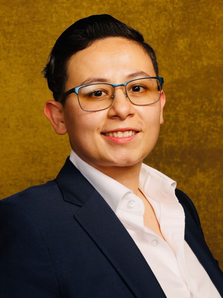 A smiling individual in professional attire exudes warmth and approachability against a golden backdrop, embodying community spirit.