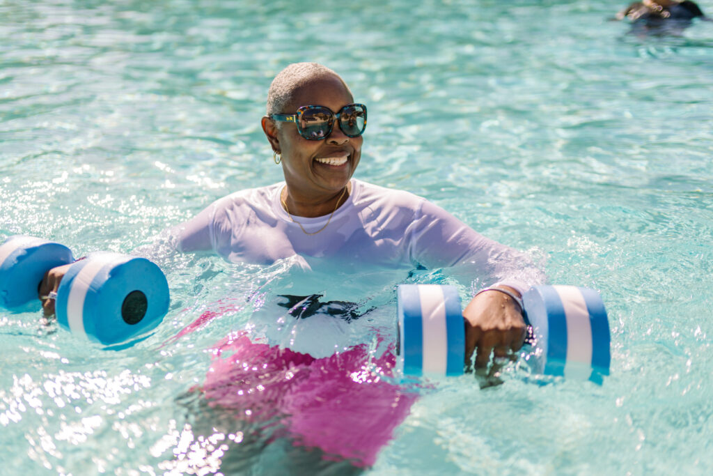 A joyful resident enjoys water aerobics, showcasing a vibrant community atmosphere and active lifestyle.