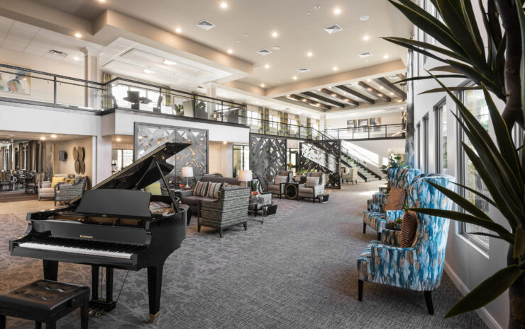 This inviting lobby features comfortable seating, a grand piano, and warm, welcoming decor, fostering community.