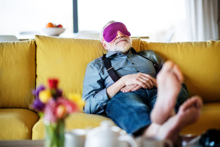 A serene moment of relaxation, showcasing a gentleman peacefully resting on a vibrant couch, surrounded by flowers.