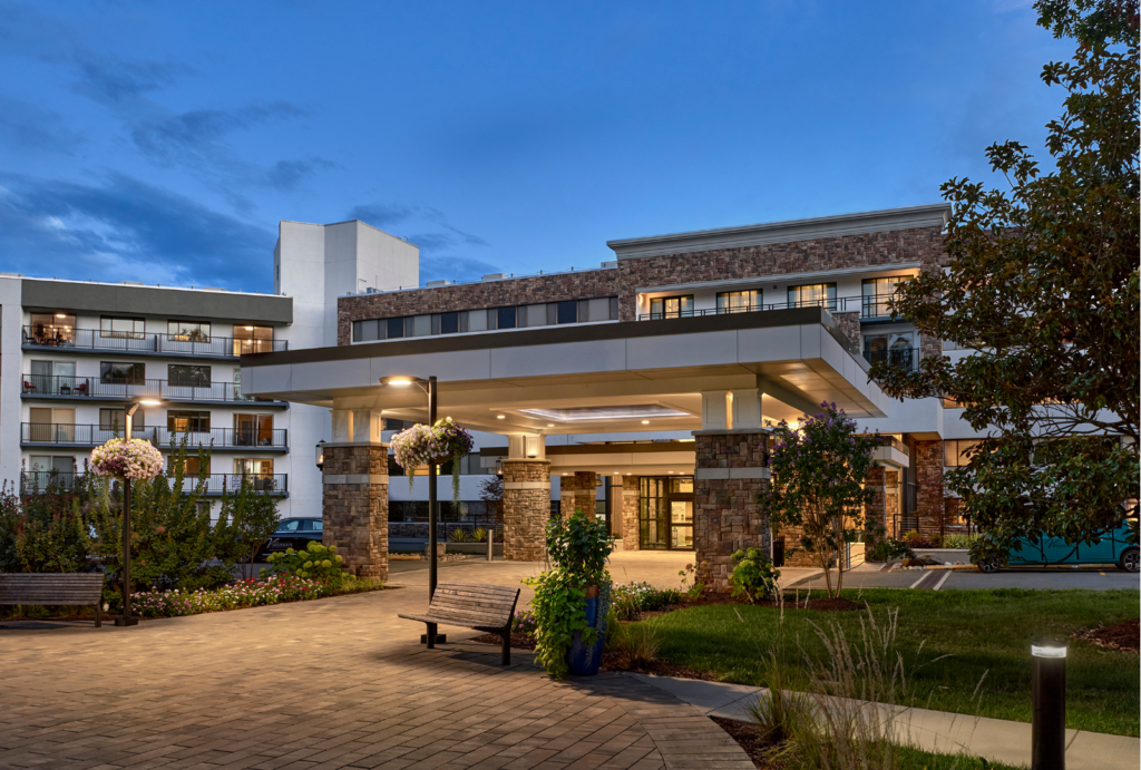 Welcoming entrance surrounded by lush gardens and inviting seating, perfect for community gatherings.