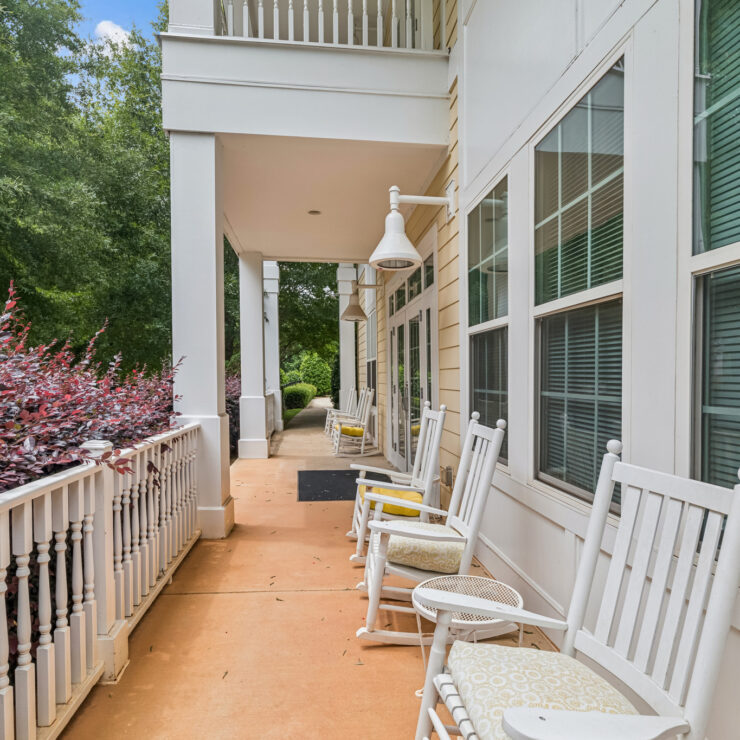 A welcoming porch lined with rocking chairs invites relaxation and connection in a serene, vibrant setting.