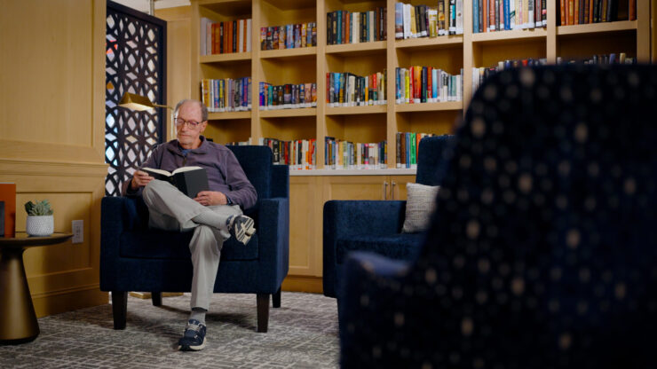 A welcoming reading nook, filled with books and a relaxed resident enjoying a peaceful moment.