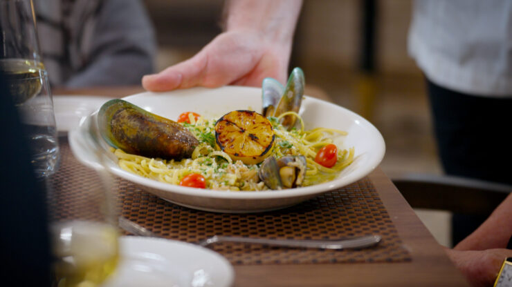 A beautifully plated seafood pasta dish, showcasing vibrant colors and inviting presentation, highlights community dining at its best.