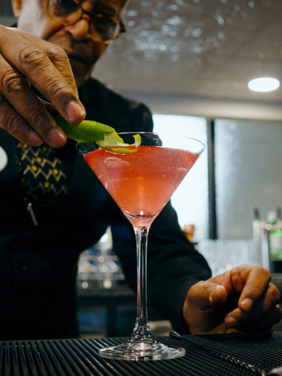 A bartender skillfully garnishes a vibrant cocktail, creating a welcoming atmosphere for residents.