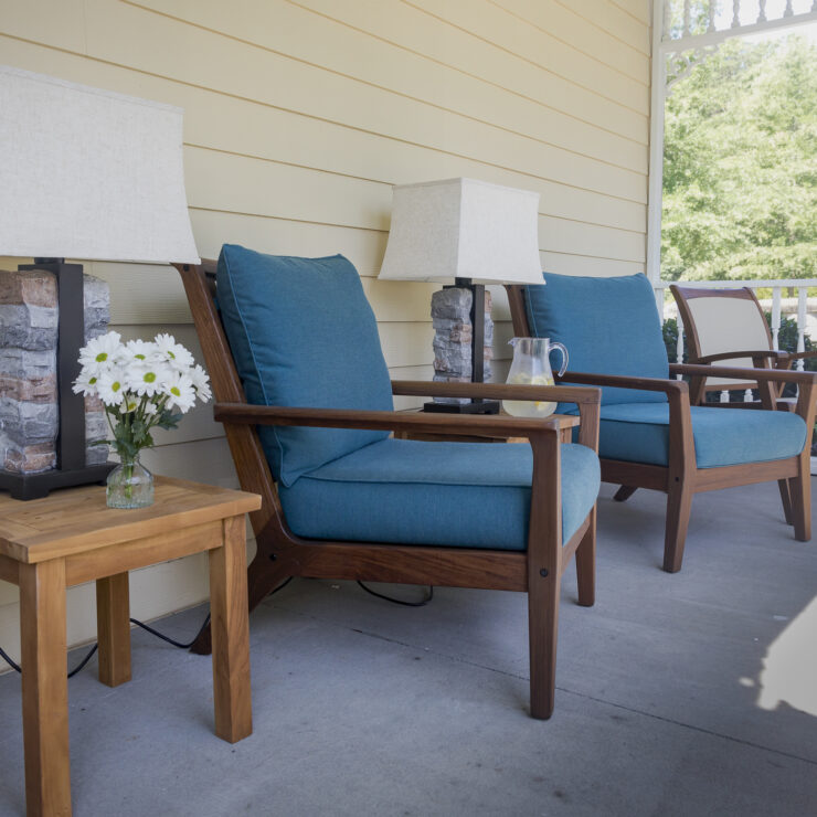 A serene porch with inviting blue chairs, soft lighting, and fresh flowers, perfect for community gatherings.