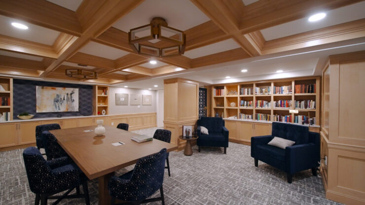 A welcoming common area featuring comfortable seating, warm lighting, and a well-stocked bookshelf, fostering community and connection.