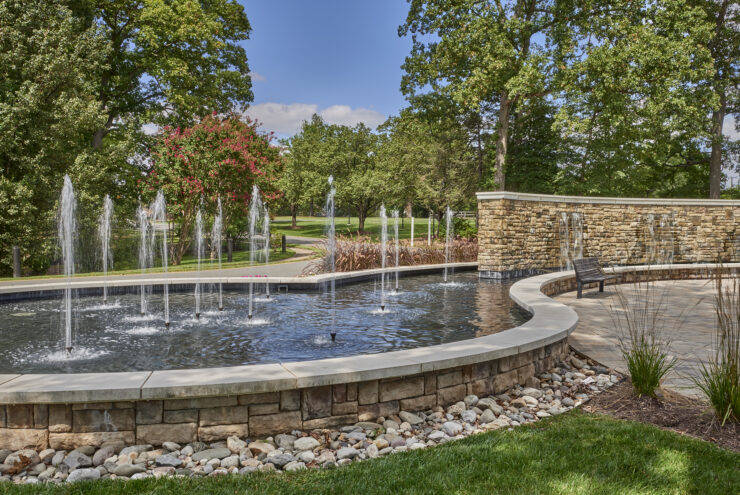 A serene outdoor space featuring a soothing fountain, surrounded by lush greenery and inviting pathways.