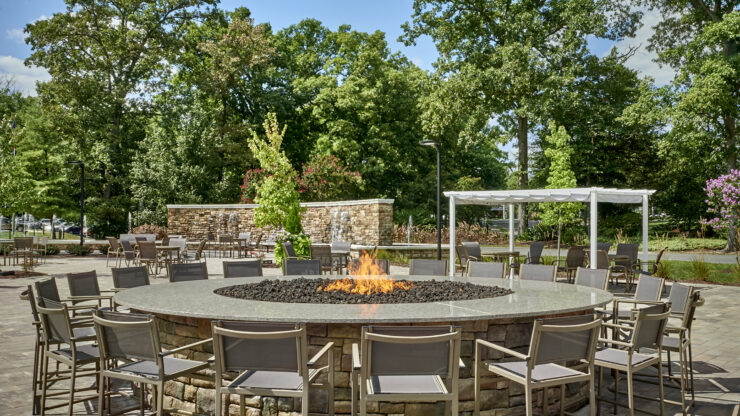 A welcoming outdoor space with a fire pit, surrounded by greenery and comfortable seating, perfect for gatherings.
