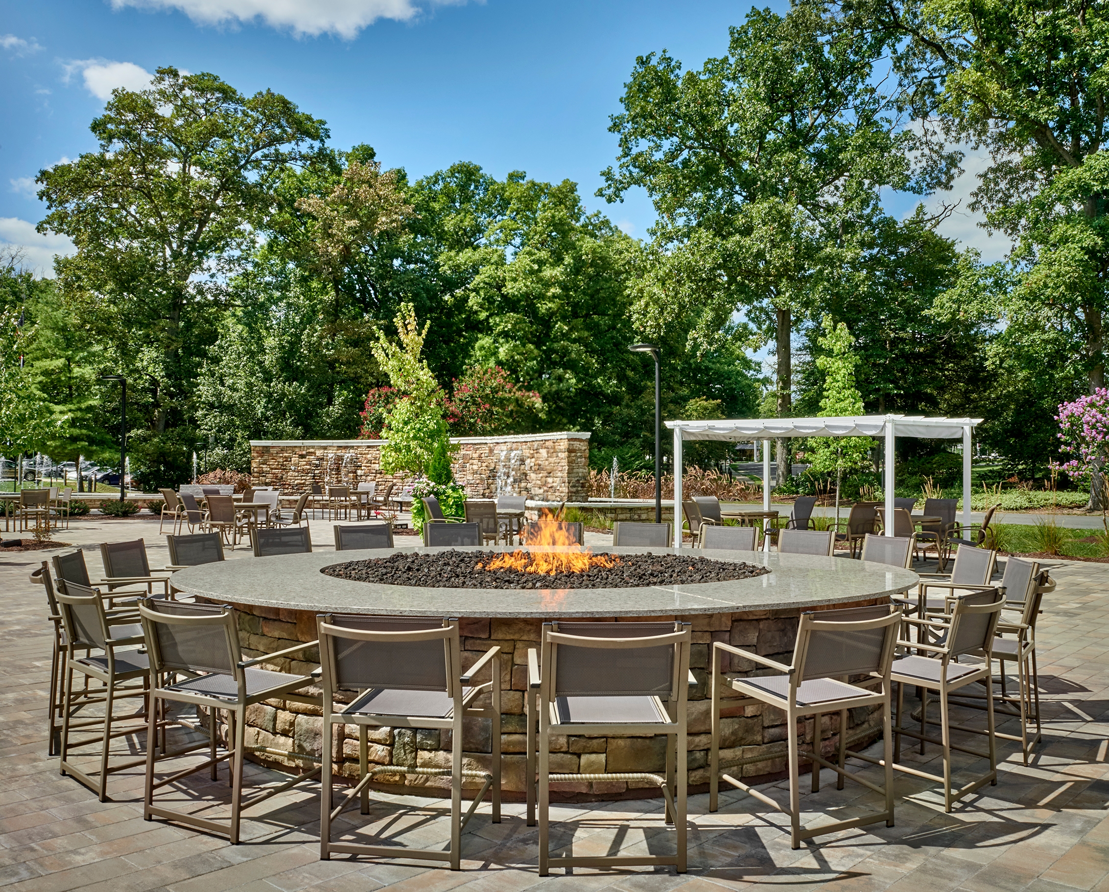 A welcoming outdoor space with a fire pit, surrounded by greenery and comfortable seating, perfect for gatherings.