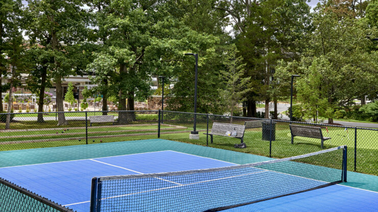 A vibrant tennis court surrounded by lush trees, inviting residents to enjoy active, social fun.