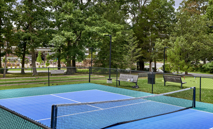 A vibrant tennis court surrounded by lush trees, inviting residents to enjoy active, social fun.