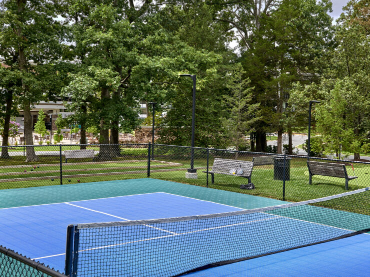 A vibrant tennis court surrounded by lush trees, inviting residents to enjoy active, social fun.