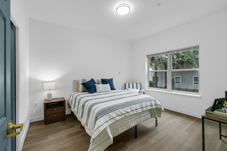 Bright, inviting room with a comfortable bed, cozy seating, and a view of lush greenery outside.