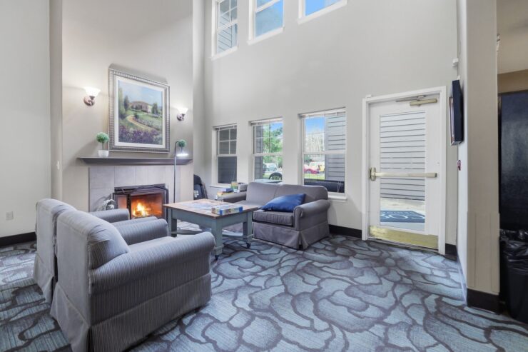 A warm, inviting lounge with comfortable seating, natural light, and a cozy fireplace, perfect for community connections.