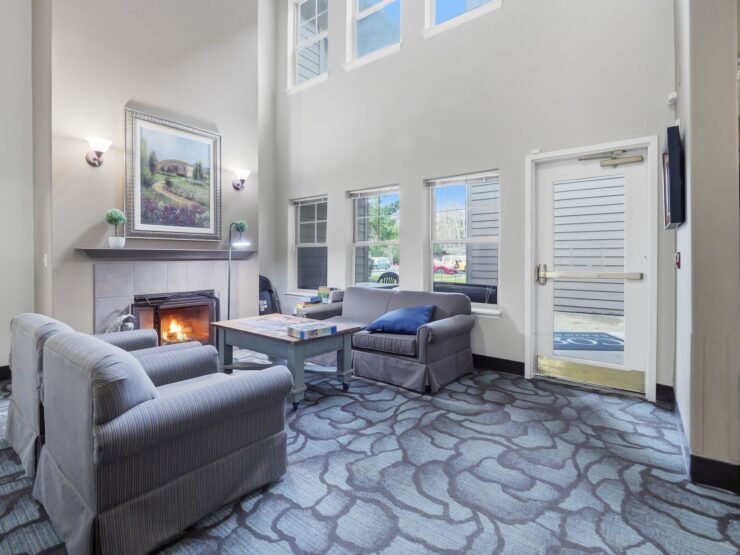 A warm, inviting lounge with comfortable seating, natural light, and a cozy fireplace, perfect for community connections.