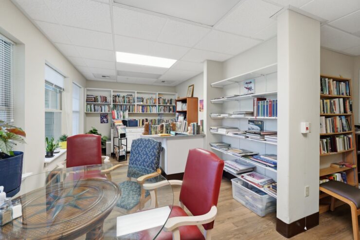 A welcoming reading nook filled with books, comfortable seating, and sunny windows invites community connection.