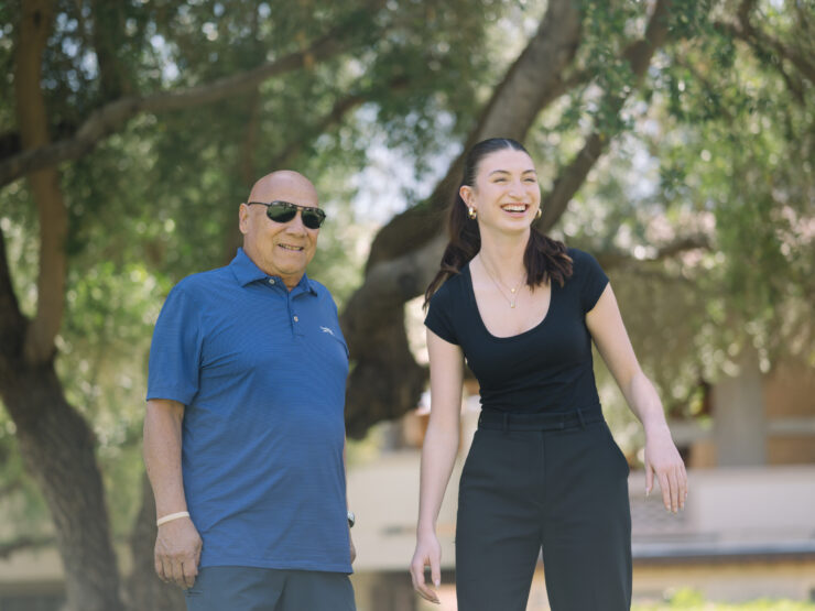 Laughter fills the air as two residents enjoy a sunny day under the trees, highlighting community joy.