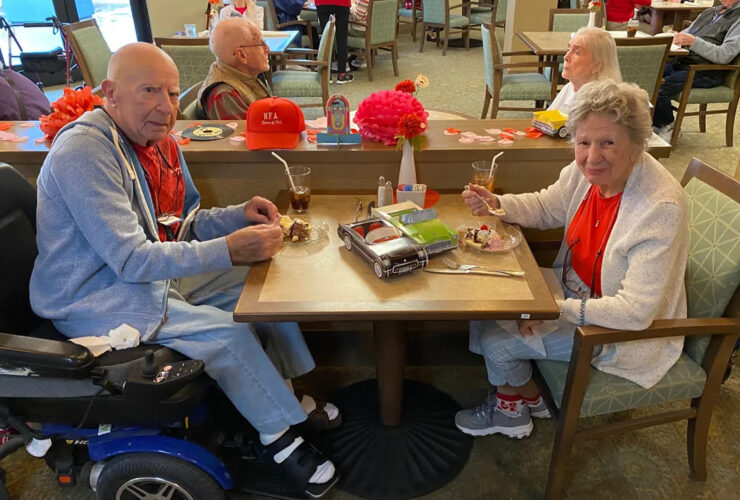 Seniors enjoying dessert together in a warm, welcoming dining area with festive decor.