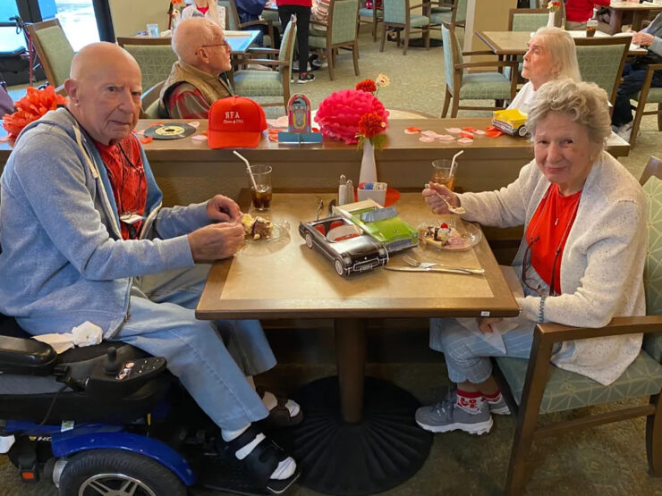 Seniors enjoying dessert together in a warm, welcoming dining area with festive decor.
