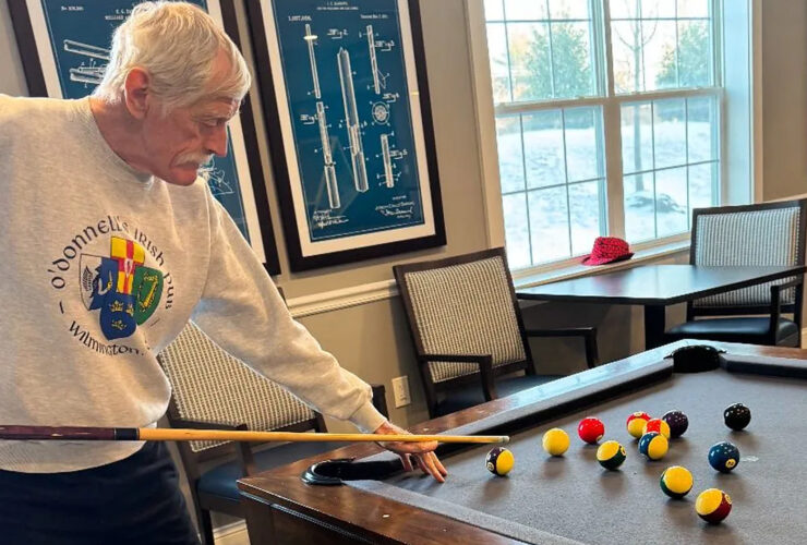 Senior man focused on a friendly game of pool in a bright, inviting community room.