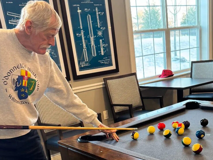 Senior man focused on a friendly game of pool in a bright, inviting community room.