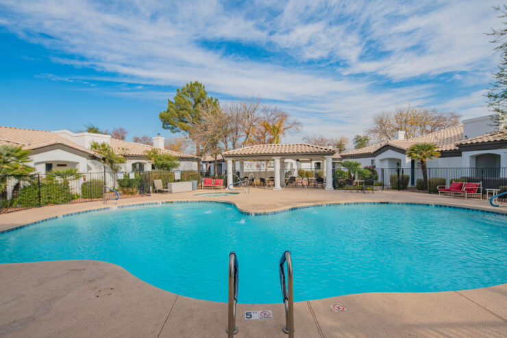 A serene pool area surrounded by inviting seating and lush greenery, perfect for community relaxation.