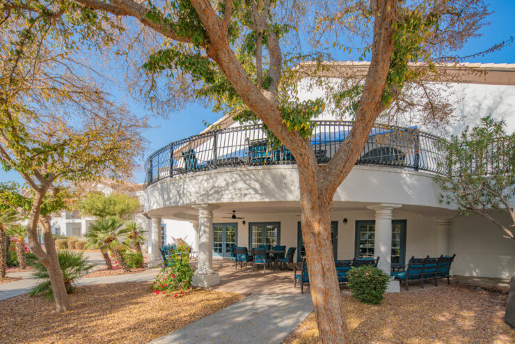 A welcoming outdoor space with lush trees and comfortable seating invites community and relaxation.