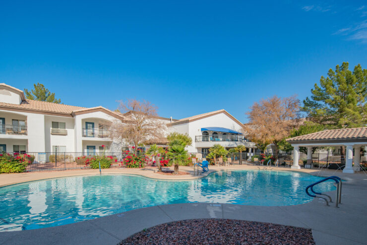 A serene pool area surrounded by vibrant flowers and welcoming architecture, perfect for community relaxation.