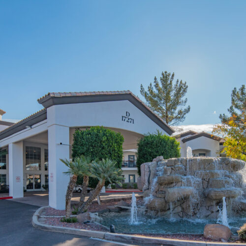 A welcoming entrance features a serene fountain and lush greenery, creating a vibrant community atmosphere.