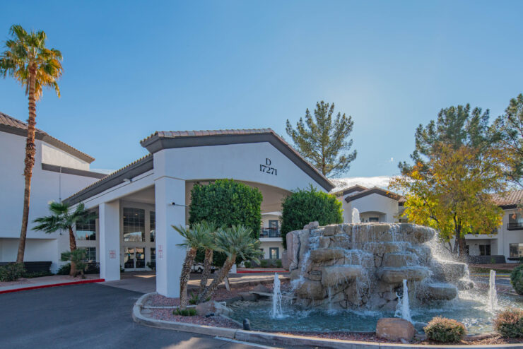 A welcoming entrance features a serene fountain and lush greenery, creating a vibrant community atmosphere.