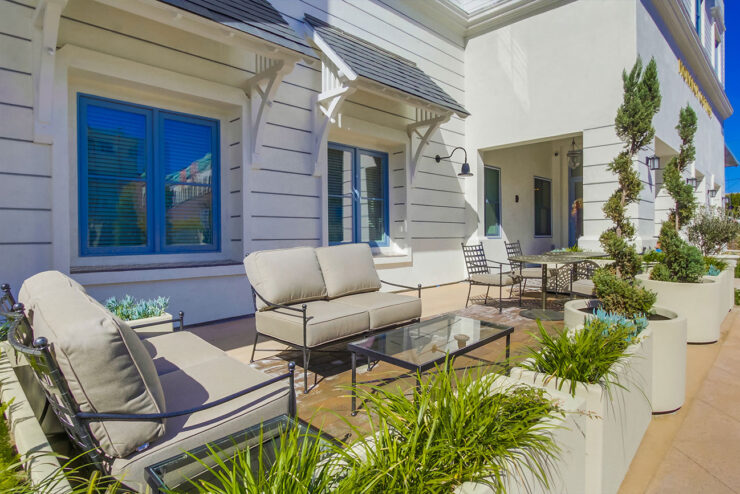 A welcoming outdoor space with comfortable seating, lush greenery, and bright blue skies, perfect for community gatherings.