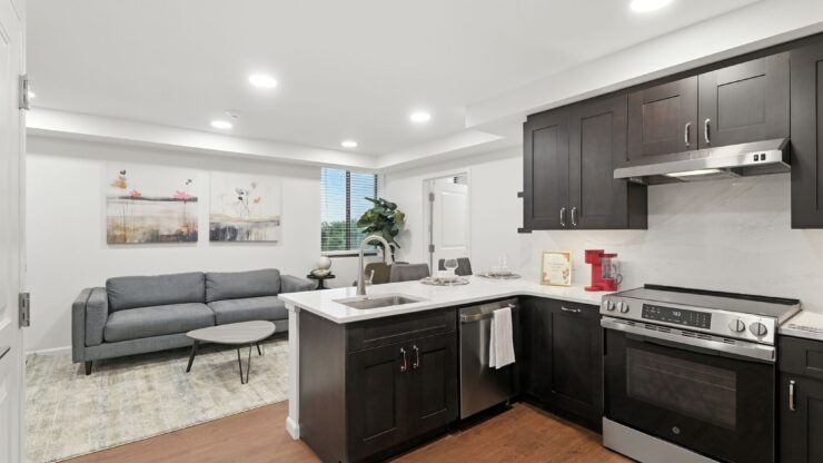 Modern kitchen and living area with dark wood cabinets, comfortable seating, and natural light.
