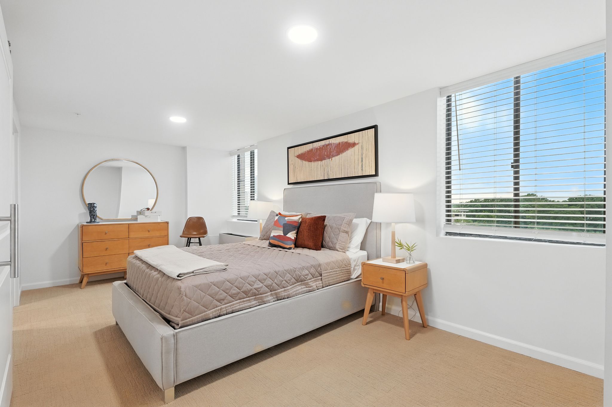 Bright, inviting bedroom with modern furnishings and large windows offering peaceful outdoor views.