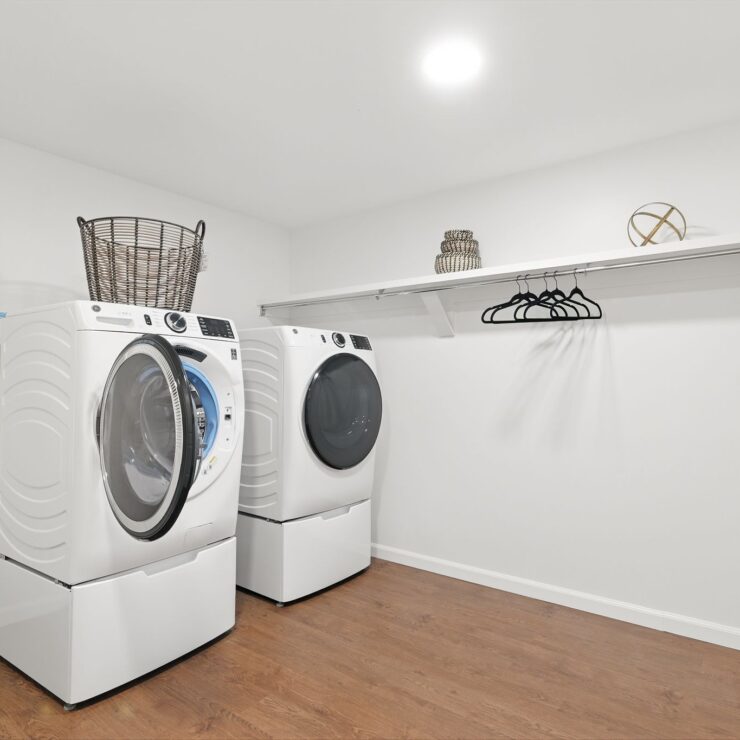 Bright, clean laundry room with modern machines and organized shelving for resident convenience.