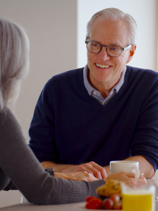 Two seniors enjoy a warm conversation over breakfast in a bright, inviting dining area.